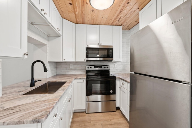 677 NE Alice St, Jensen Beach, FL 34957 - kitchen featuring stainless steel appliances, a sink, wood ceiling, and white cabinets