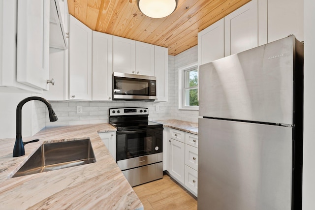 677 NE Alice St, Jensen Beach, FL 34957 - kitchen with stainless steel appliances, a sink, wood ceiling, and white cabinets