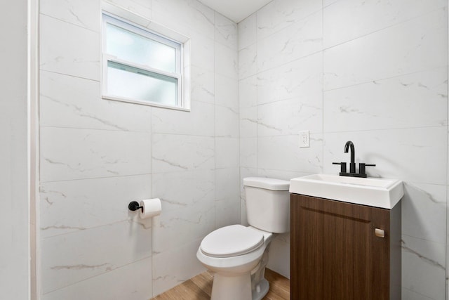 677 NE Alice St, Jensen Beach, FL 34957 - half bath featuring toilet, vanity, wood finished floors, and tile walls