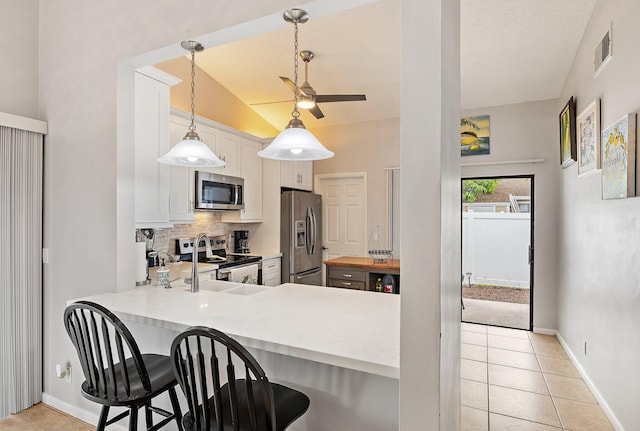 202 Lakewood Dr Unit 11C, Jupiter, FL 33458 - kitchen with stainless steel appliances, tasteful backsplash, light countertops, a breakfast bar, and a ceiling fan