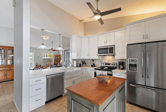 202 Lakewood Dr Unit 11C, Jupiter, FL 33458 - kitchen with appliances with stainless steel finishes, a ceiling fan, tasteful backsplash, light tile patterned floors, and high vaulted ceiling