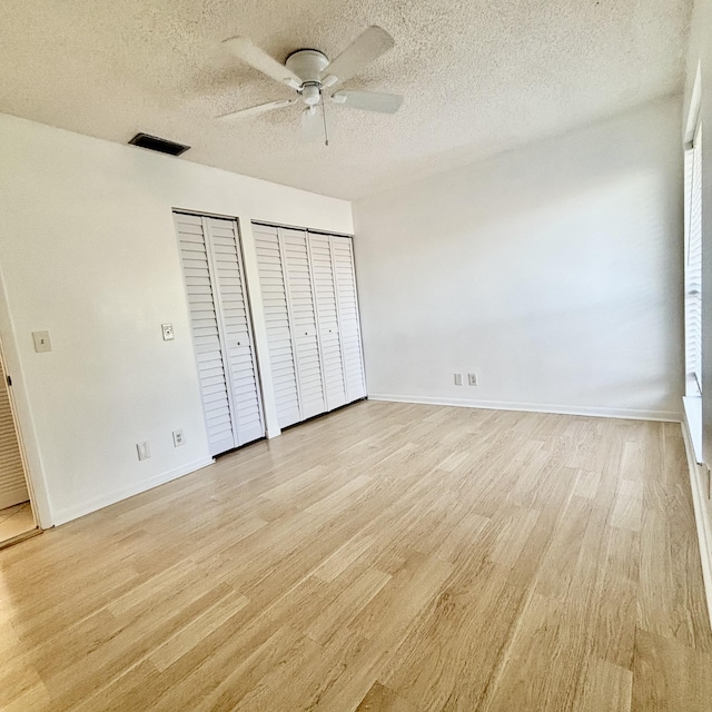 727 Sunny Pine Way Unit H, Greenacres, FL 33415 - unfurnished bedroom with two closets, light wood-style floors, a textured ceiling, baseboards, and ceiling fan