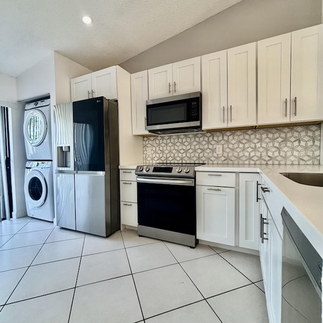 727 Sunny Pine Way Unit H, Greenacres, FL 33415 - kitchen with appliances with stainless steel finishes, stacked washer / dryer, light countertops, tasteful backsplash, and white cabinets