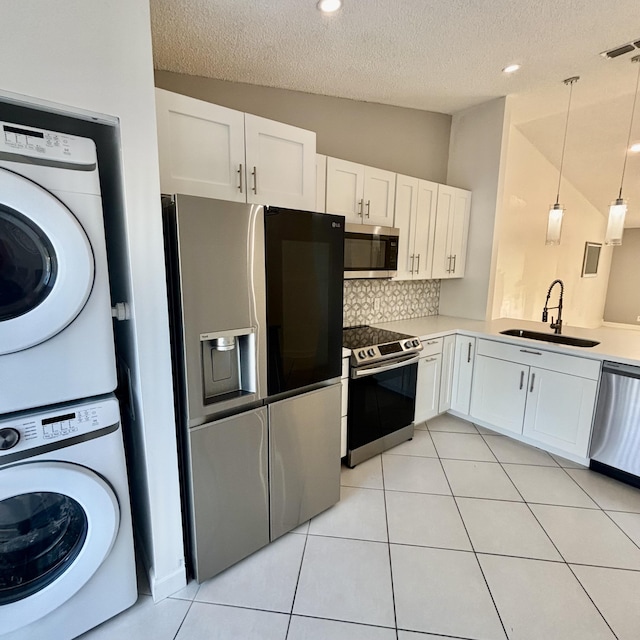 727 Sunny Pine Way Unit H, Greenacres, FL 33415 - kitchen featuring appliances with stainless steel finishes, a sink, stacked washer / dryer, lofted ceiling, and a textured ceiling