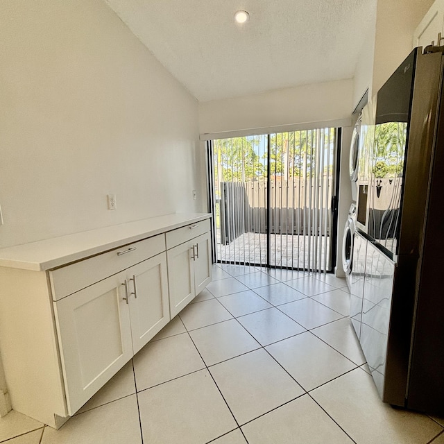 727 Sunny Pine Way Unit H, Greenacres, FL 33415 - empty room featuring stacked washing machine and dryer, vaulted ceiling, a textured ceiling, and light tile patterned flooring