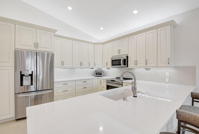 13209 Alhambra Lake Cir, Delray Beach, FL 33446 - kitchen with appliances with stainless steel finishes, a kitchen breakfast bar, lofted ceiling, decorative backsplash, and a peninsula