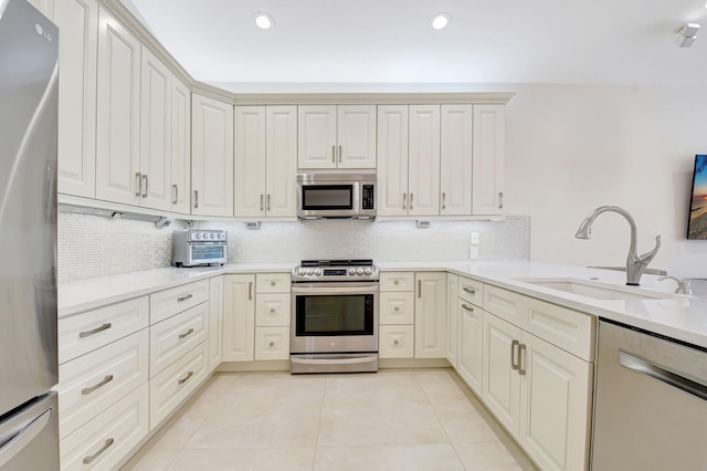 13209 Alhambra Lake Cir, Delray Beach, FL 33446 - kitchen with stainless steel appliances, a sink, light tile patterned flooring, tasteful backsplash, and light countertops