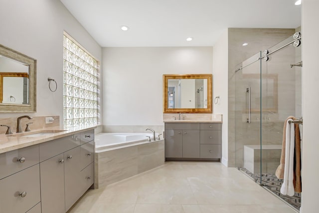 13209 Alhambra Lake Cir, Delray Beach, FL 33446 - bathroom featuring healthy amount of natural light, a stall shower, a garden tub, two vanities, and recessed lighting