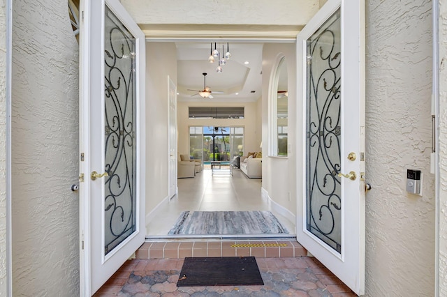13209 Alhambra Lake Cir, Delray Beach, FL 33446 - entryway featuring a tray ceiling, ceiling fan, a textured wall, arched walkways, and tile patterned flooring