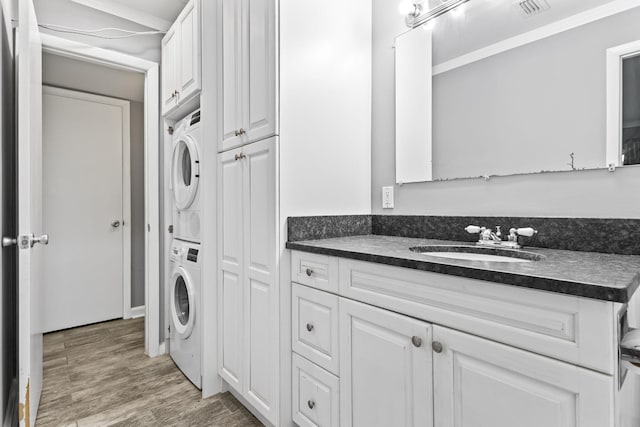 8 Vista Palm Ln Unit 103, Vero Beach, FL 32962 - bathroom featuring stacked washing machine and dryer, vanity, and wood finished floors