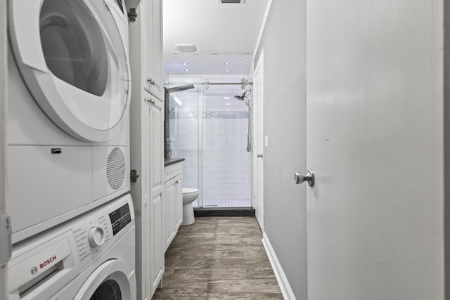 8 Vista Palm Ln Unit 103, Vero Beach, FL 32962 - washroom with estacked washer and dryer, dark wood-type flooring, and baseboards