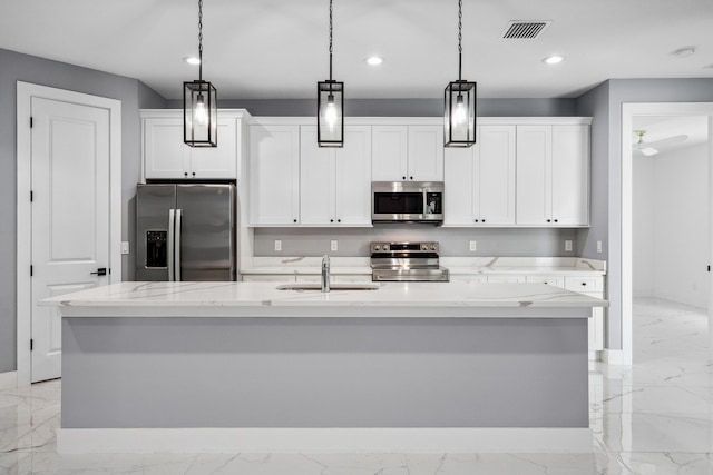 2265 SW Kenwick Ave, Port Saint Lucie, FL 34953 - kitchen featuring appliances with stainless steel finishes, light marble finish flooring, recessed lighting, a center island with sink, and white cabinets