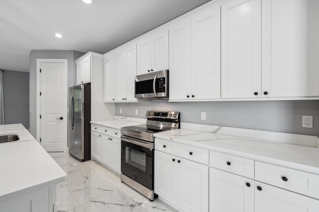 2265 SW Kenwick Ave, Port Saint Lucie, FL 34953 - kitchen featuring appliances with stainless steel finishes, light marble finish flooring, recessed lighting, white cabinets, and light stone countertops