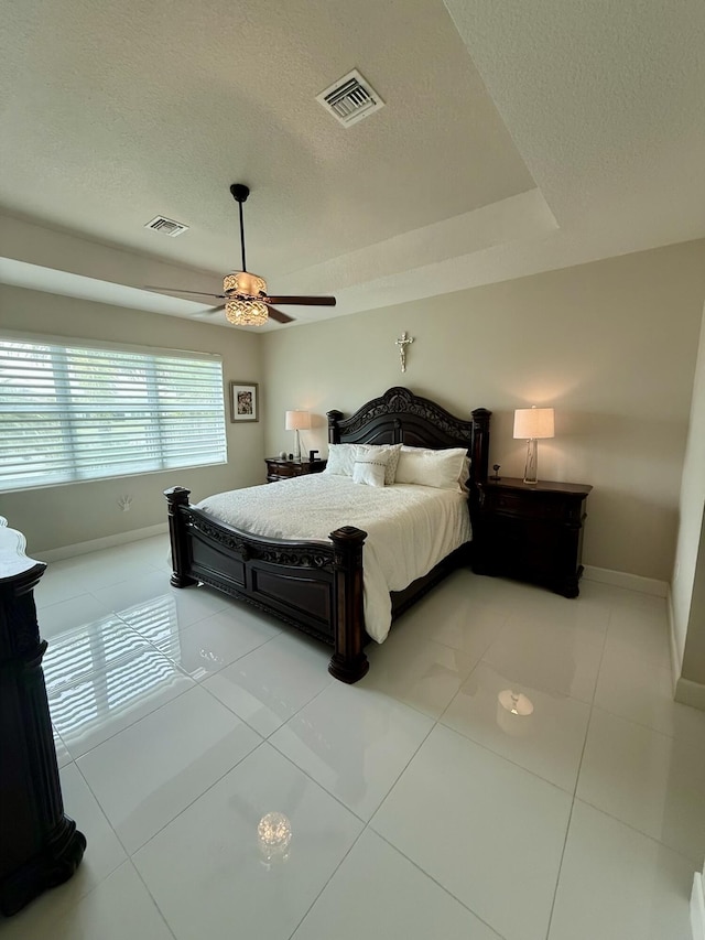 10876 SW Sunray St, Port Saint Lucie, FL 34987 - bedroom with a textured ceiling, baseboards, light tile patterned floors, ceiling fan, and a tray ceiling