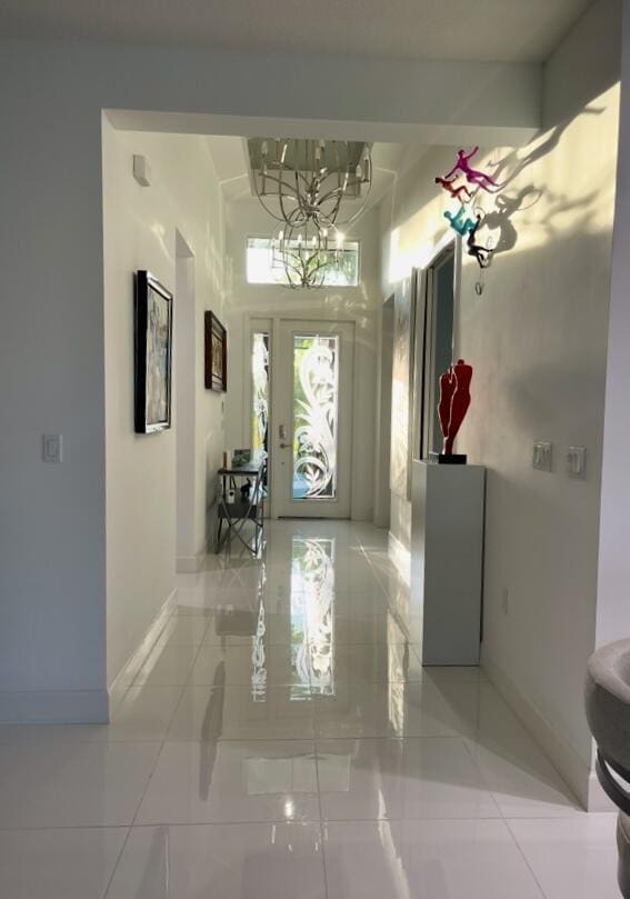 10876 SW Sunray St, Port Saint Lucie, FL 34987 - foyer entrance with baseboards, light tile patterned floors, and a chandelier