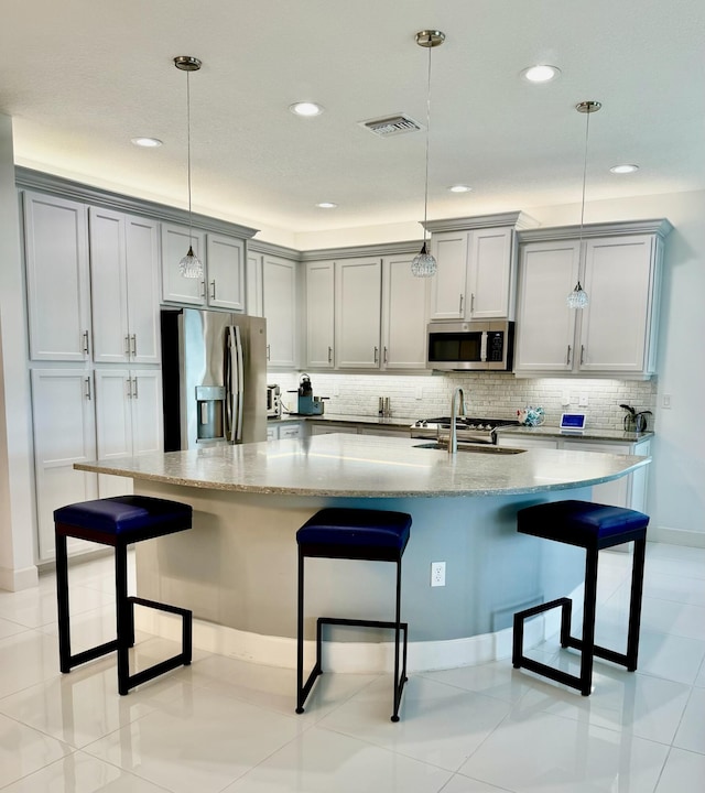 10876 SW Sunray St, Port Saint Lucie, FL 34987 - kitchen with appliances with stainless steel finishes, tasteful backsplash, light stone counters, a breakfast bar area, and recessed lighting