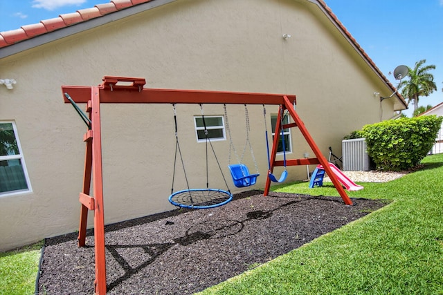 11080 Lakeaire Cir, Boca Raton, FL 33498 - rear view of house featuring a playground, stucco siding, central air condition unit, and a lawn
