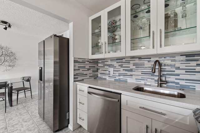 1116 Cambridge E Unit E, Deerfield Beach, FL 33442 - kitchen featuring stainless steel appliances, backsplash, a textured ceiling, glass insert cabinets, and light stone countertops