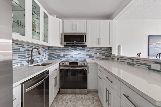 1116 Cambridge E Unit E, Deerfield Beach, FL 33442 - kitchen featuring stainless steel appliances, white cabinetry, tasteful backsplash, glass insert cabinets, and light stone counters