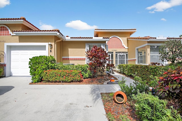 12562 Crystal Pointe Dr Unit B, Boynton Beach, FL 33437 - mediterranean / spanish-style house with an attached garage, stucco siding, a tiled roof, and driveway