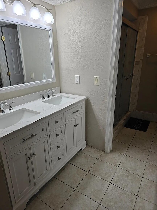 12 Via De Casas Sur Unit 203, Boynton Beach, FL 33426 - bathroom featuring a textured wall, double vanity, a shower stall, and tile patterned floors