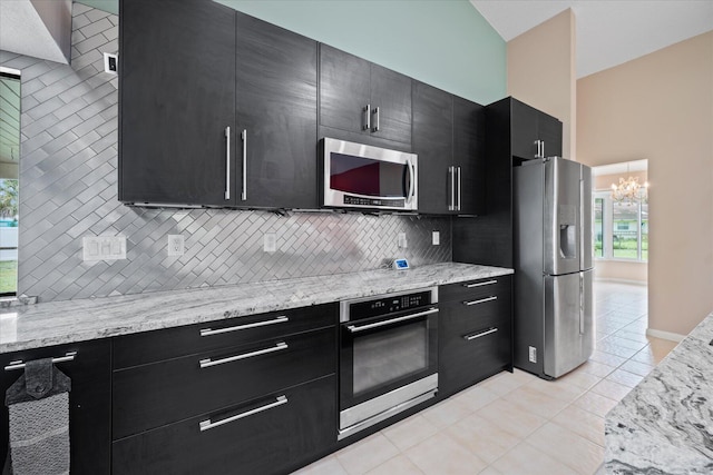 11038 Monet Ln, Palm Beach Gardens, FL 33410 - kitchen with stainless steel appliances, dark cabinets, decorative backsplash, light tile patterned floors, and a chandelier