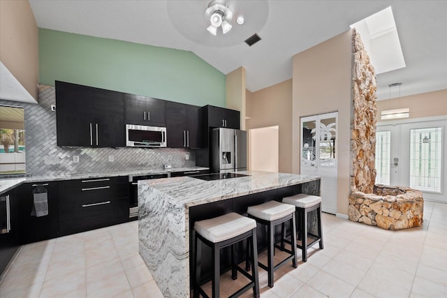 11038 Monet Ln, Palm Beach Gardens, FL 33410 - kitchen with dark cabinets, appliances with stainless steel finishes, a center island, tasteful backsplash, and a ceiling fan