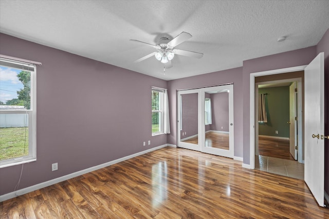 11038 Monet Ln, Palm Beach Gardens, FL 33410 - unfurnished bedroom featuring wood finished floors, multiple windows, a textured ceiling, and ceiling fan