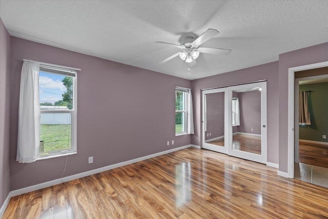 11038 Monet Ln, Palm Beach Gardens, FL 33410 - unfurnished bedroom featuring wood finished floors, a textured ceiling, a ceiling fan, and french doors
