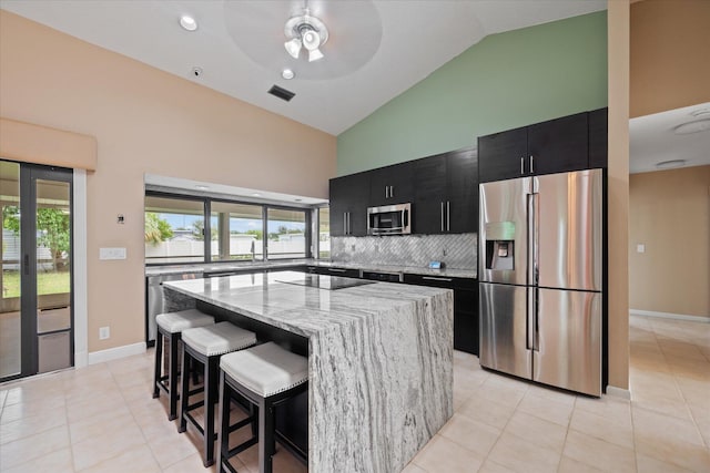 11038 Monet Ln, Palm Beach Gardens, FL 33410 - kitchen featuring appliances with stainless steel finishes, dark cabinetry, high vaulted ceiling, a center island, and a kitchen breakfast bar