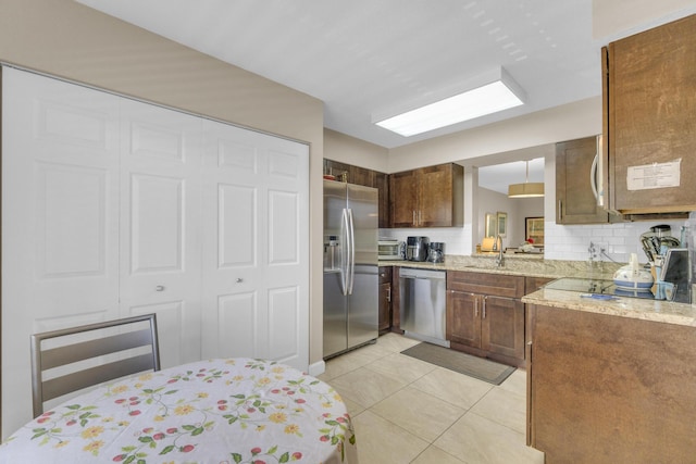 14375 Strathmore Ln Unit 306, Delray Beach, FL 33446 - kitchen featuring appliances with stainless steel finishes, light tile patterned floors, backsplash, light stone countertops, and brown cabinetry