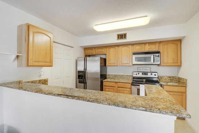 261 SW Palm Dr Unit 205, Port Saint Lucie, FL 34986 - kitchen with stainless steel appliances, light brown cabinets, light tile patterned floors, and a peninsula