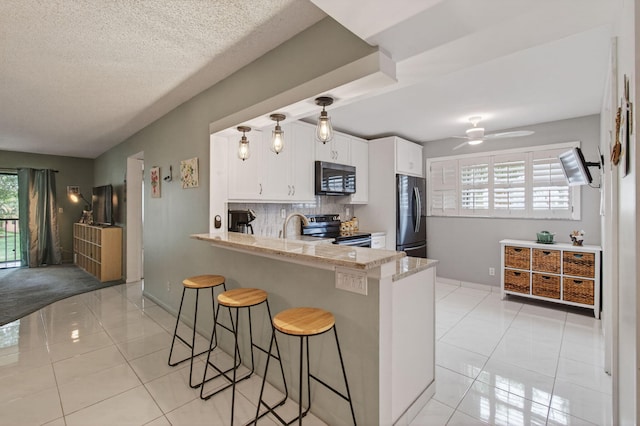 15450 Pembridge Ave Unit 189, Delray Beach, FL 33484 - kitchen with appliances with stainless steel finishes, white cabinets, light tile patterned flooring, a peninsula, and a textured ceiling