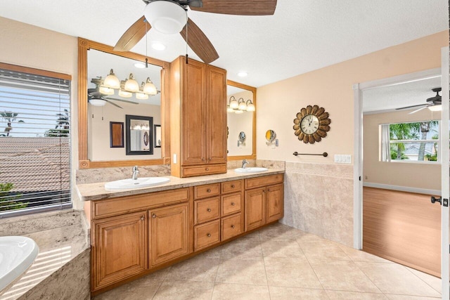 9556 E Lake Dr, Boca Raton, FL 33434 - bathroom featuring a ceiling fan, double vanity, a bathtub, tile patterned floors, and tile walls