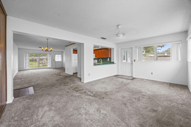 5557 S Shadyside Cir, West Palm Beach, FL 33415 - unfurnished living room with a chandelier, a textured ceiling, carpet floors, healthy amount of natural light, and baseboards