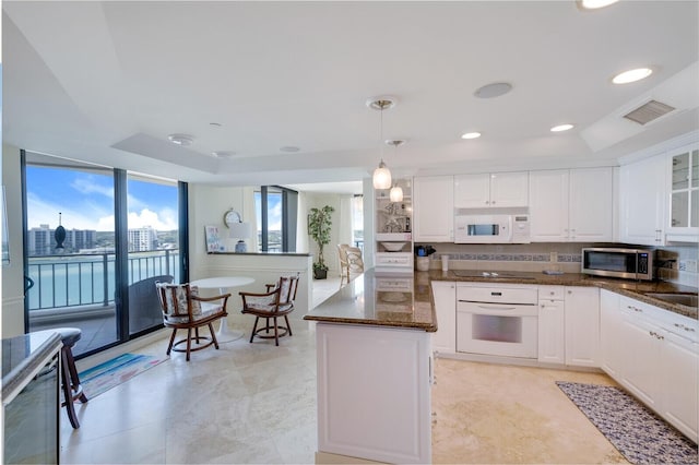 19850 Beach Rd Unit 8D, Jupiter, FL 33469 - kitchen featuring white appliances, white cabinetry, glass insert cabinets, a peninsula, and dark stone countertops