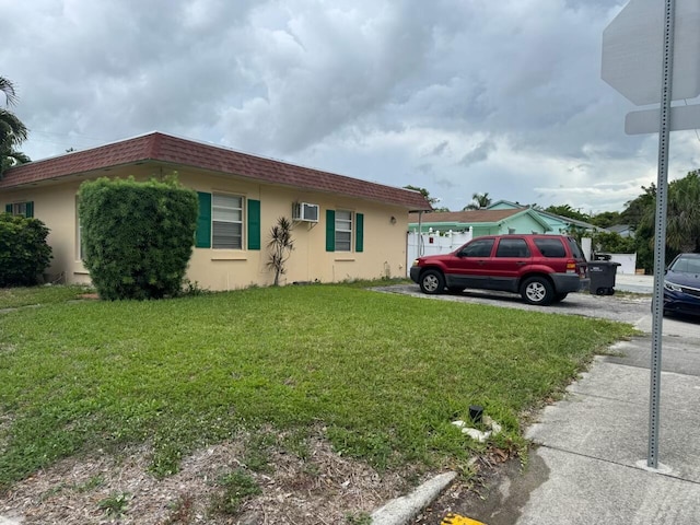 4601 Lake Ave, West Palm Beach, FL 33405 - view of front of house featuring an AC wall unit, stucco siding, a front lawn, and mansard roof