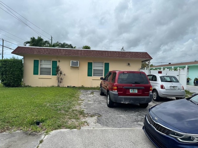 4601 Lake Ave, West Palm Beach, FL 33405 - ranch-style house featuring stucco siding, a wall unit AC, mansard roof, roof with shingles, and a front lawn