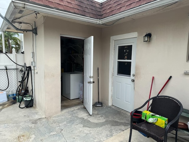 4601 Lake Ave, West Palm Beach, FL 33405 - doorway to property featuring a shingled roof, stucco siding, washer / clothes dryer, and mansard roof