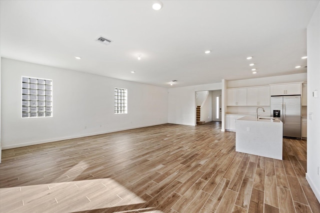18478 Claybrook St, Jupiter, FL 33458 - unfurnished living room with a sink, light wood-type flooring, stairway, baseboards, and recessed lighting