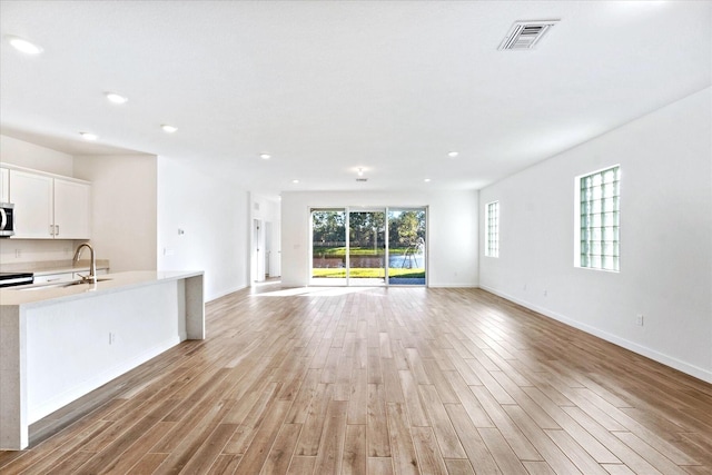 18478 Claybrook St, Jupiter, FL 33458 - unfurnished living room featuring light wood finished floors, baseboards, a sink, and recessed lighting