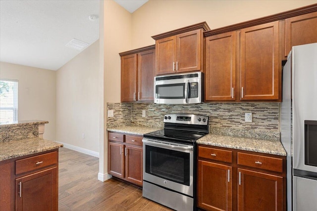 3650 SW Parsons St, Port Saint Lucie, FL 34953 - kitchen with stainless steel appliances, wood finished floors, decorative backsplash, baseboards, and light stone counters