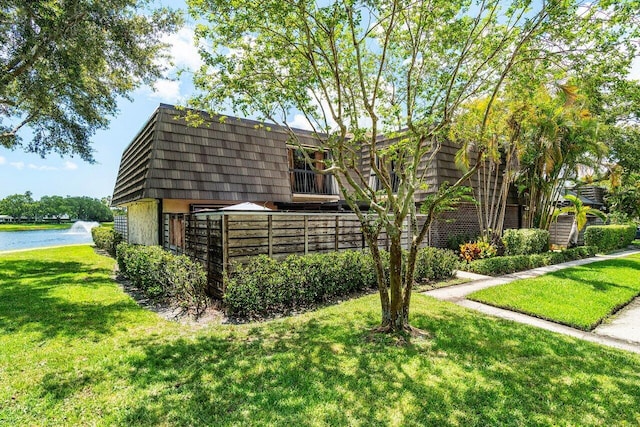 125 1st Ter, Palm Beach Gardens, FL 33418 - view of front facade with mansard roof, a front lawn, and a water view