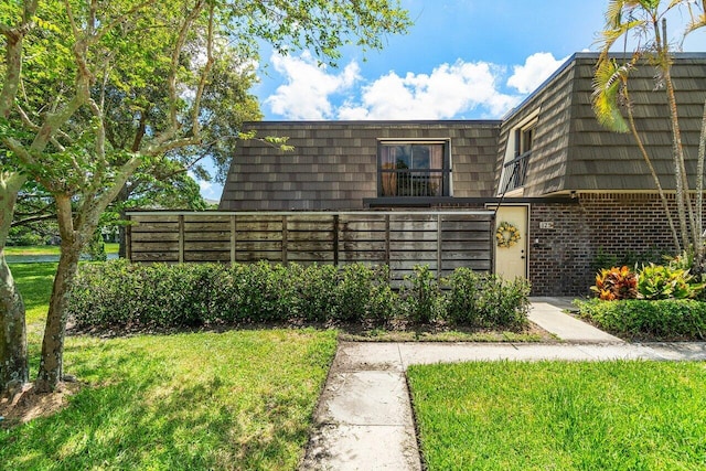 125 1st Ter, Palm Beach Gardens, FL 33418 - view of front facade with mansard roof, brick siding, and a front lawn