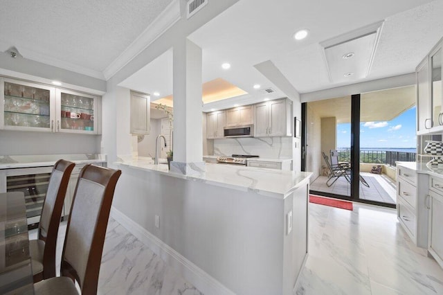 8750 S Ocean Dr Unit 731, Jensen Beach, FL 34957 - kitchen with stainless steel appliances, ornamental molding, light marble finish flooring, light stone countertops, and glass insert cabinets