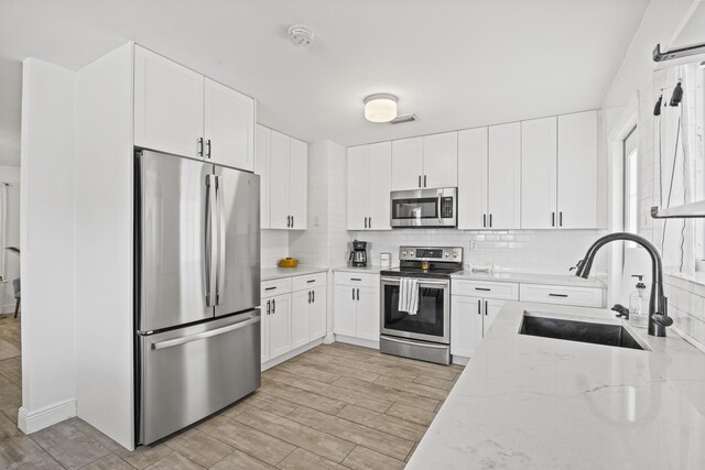 407 Riverside Dr, Palm Beach Gardens, FL 33410 - kitchen with stainless steel appliances, tasteful backsplash, light stone counters, and white cabinets