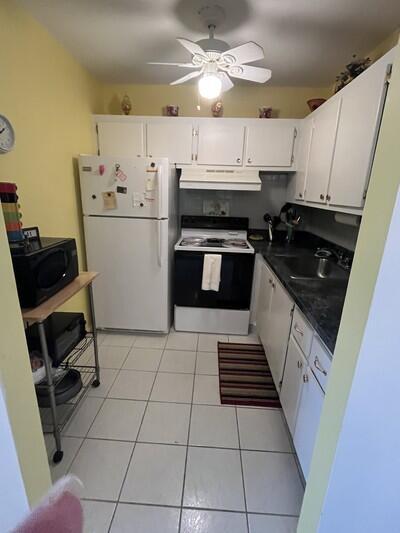 50 Berkshire B 50, West Palm Beach, FL 33417 - kitchen featuring white appliances, under cabinet range hood, a sink, dark countertops, and white cabinetry