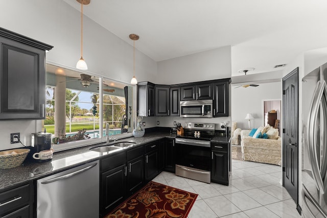 165 SE Osprey Rdg, Port Saint Lucie, FL 34984 - kitchen with appliances with stainless steel finishes, a sink, a ceiling fan, dark stone counters, and a towering ceiling