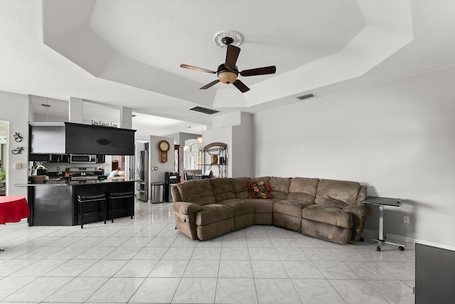 165 SE Osprey Rdg, Port Saint Lucie, FL 34984 - living area featuring a ceiling fan, a tray ceiling, and light tile patterned flooring
