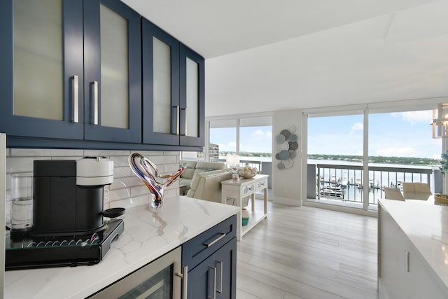 123 Lakeshore Dr Unit 1145, North Palm Beach, FL 33408 - kitchen with light wood finished floors, light stone countertops, tasteful backsplash, a water view, and glass insert cabinets